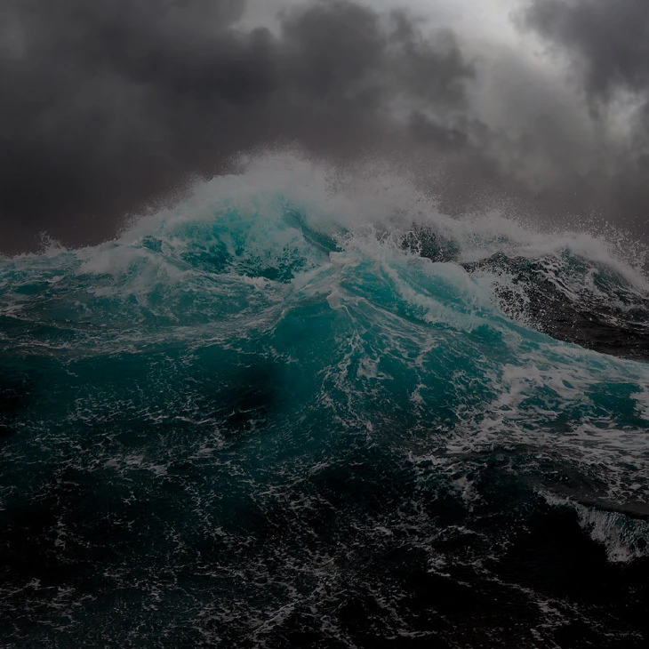 Large turquoise ocean wave breaking under dark storm clouds, dramatic stormy sea photo with no text