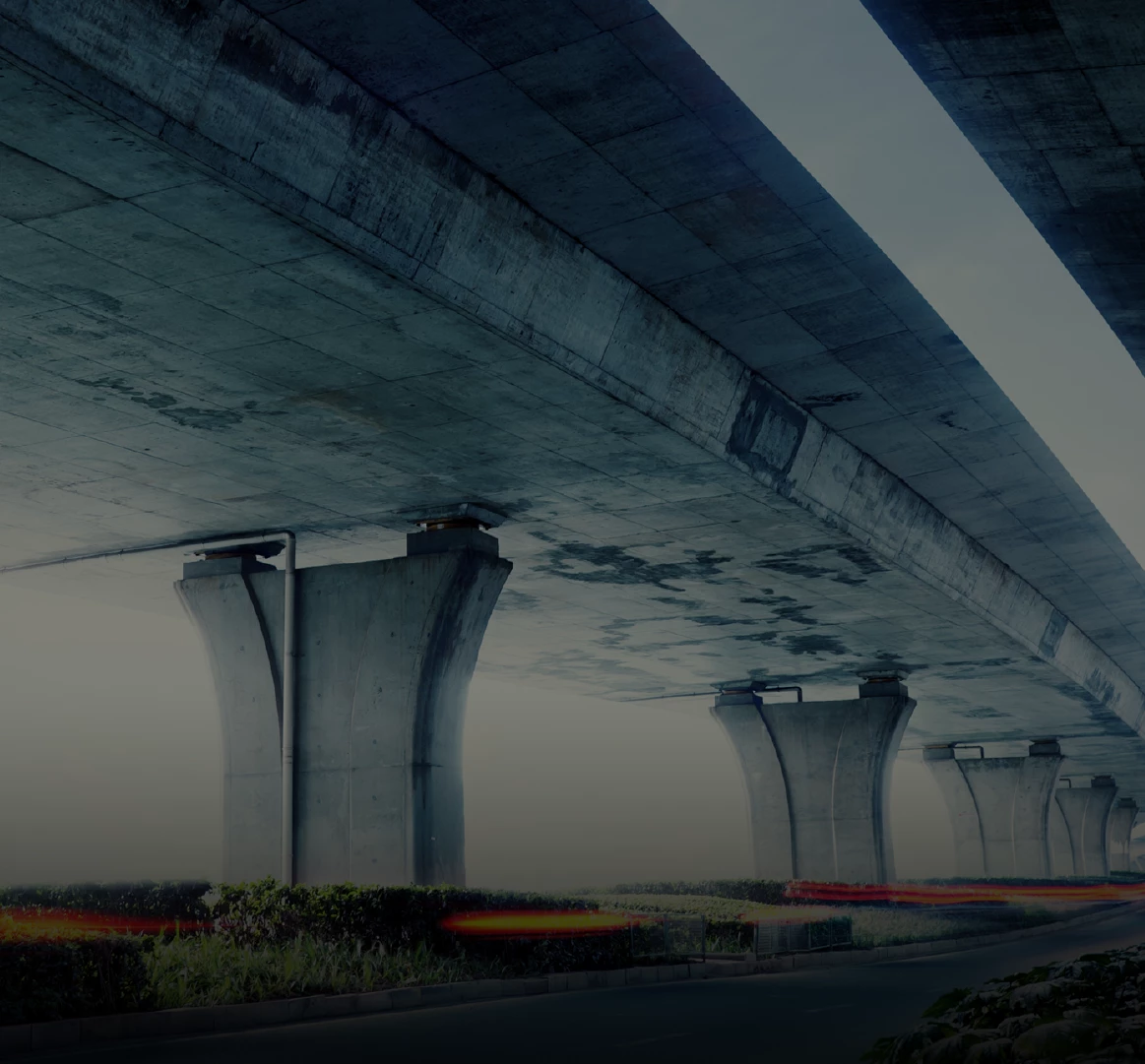 Concrete elevated highway viaduct with tapered pillars and light trails at dusk, dark blue-gray moody photo, no on-image text
