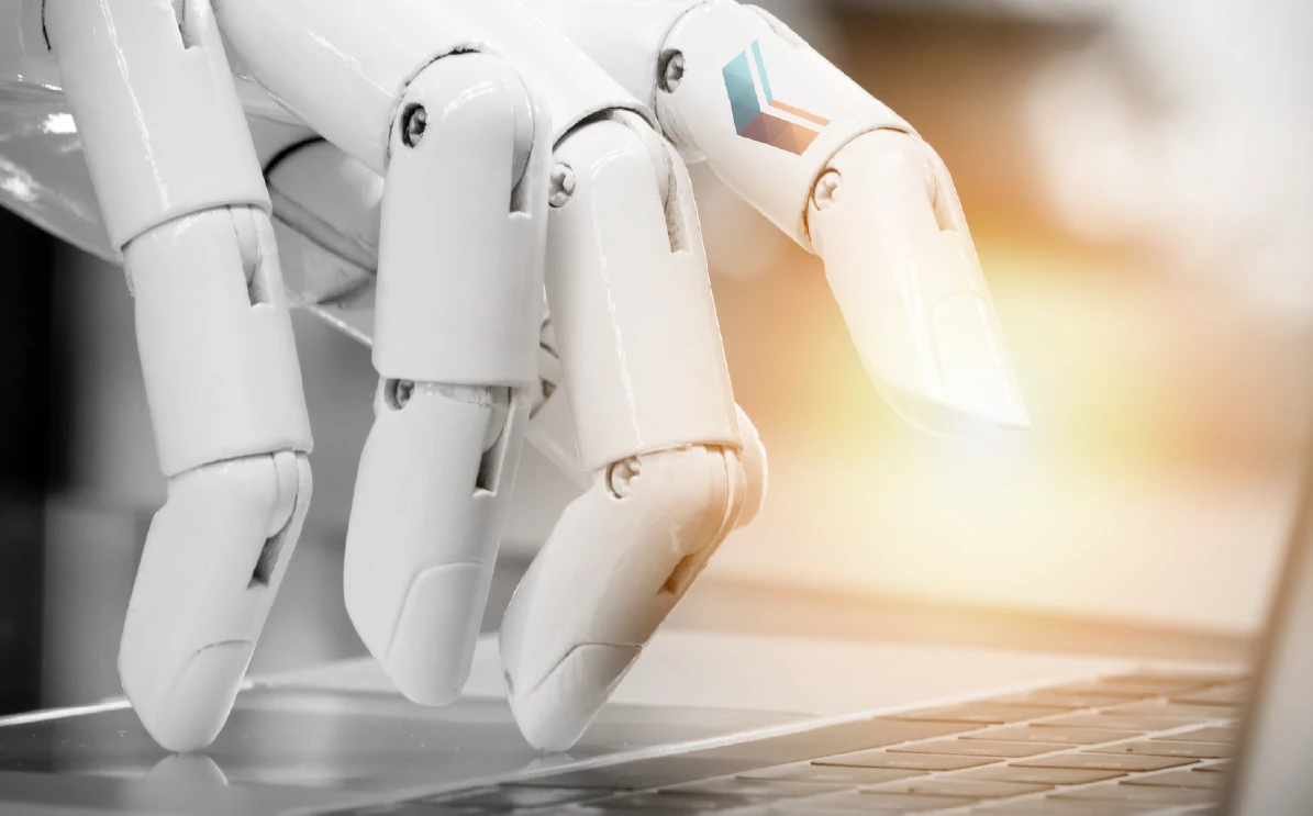 White robotic hand with glowing fingertip typing on a laptop keyboard, small blue-and-orange cube logo on the finger