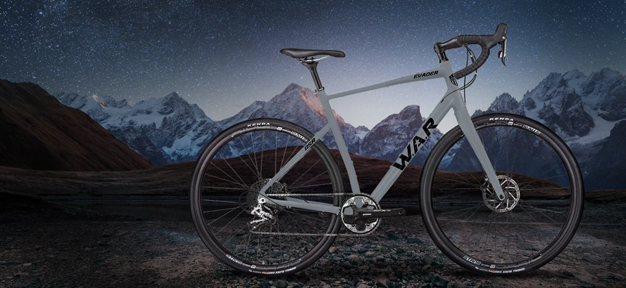 Gray WAR Evader gravel bike against snow-capped mountains under a starry night sky, Kenda tires, product