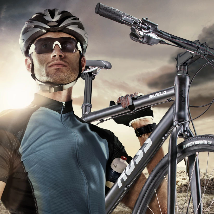 Cyclist in helmet and sunglasses carrying a black BRUNELLO road bike on his shoulder, Kwik Bitumen tire, dramatic cloudy sky